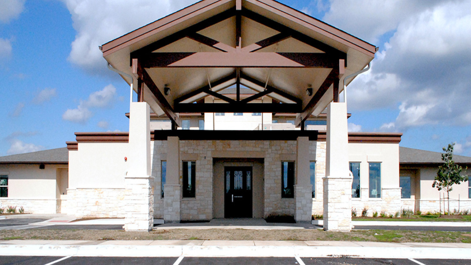 The image depicts a building that Bell County will use for the development of the Diversion Center (opening September 2023). The building is spacious and has two column beams on the left- and right-hand side. In the center is a doorway surrounded by two windows. The location has ample parking available for guests.