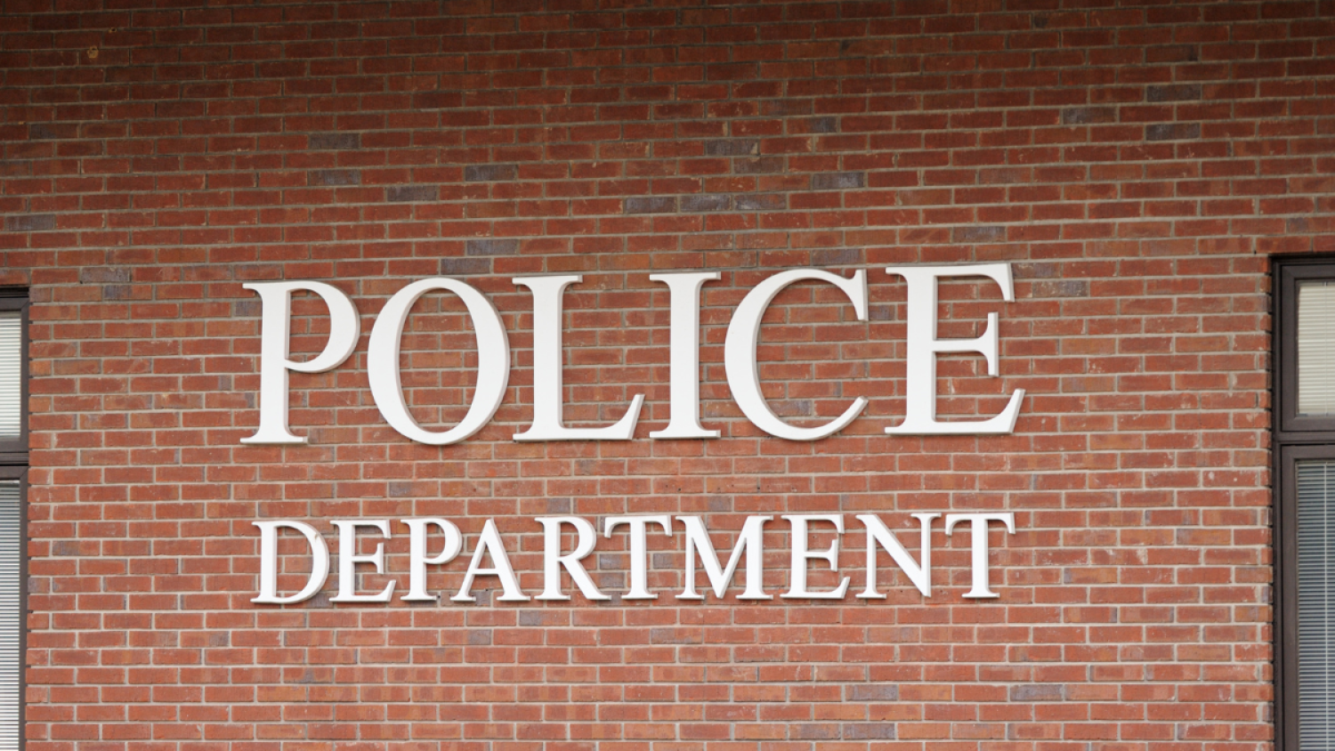 A sign reading "Police Department" on a red brick building.