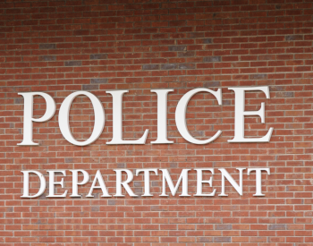A sign reading "Police Department" on a red brick building.