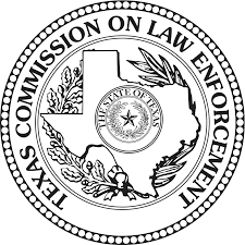 The Texas Commission on Law Enforcement logo prominently displays the Texas Seal as its central element, incorporating a distinct modification. Instead of a traditional five-pointed star, the logo features a shape of Texas within the seal, representing the state's significance to law enforcement. Inside the Texas shape, an original Texas Seal is nestled, emphasizing the Commission's authority and jurisdiction. The title "Texas Commission on Law Enforcement" wraps along the top of the outer circle border, ensuring clear identification of the organization. This logo symbolizes the Commission's role in overseeing law enforcement standards and regulations within the state of Texas.